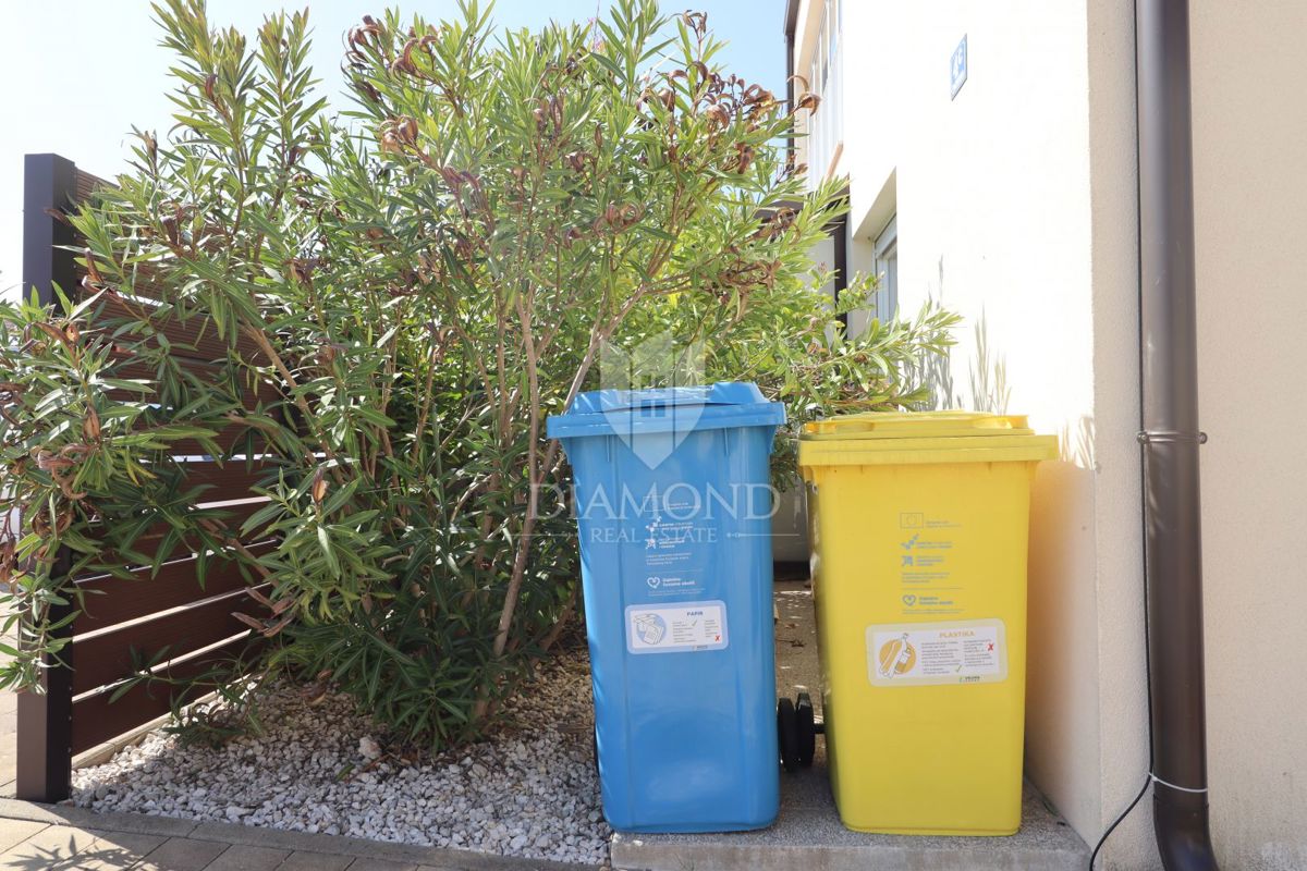 Nuova costruzione! Appartamento trilocale al piano terra con ampio giardino e parcheggio. A 1 km dal mare, nel centro del paese.