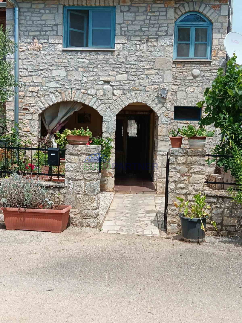 Una casa in pietra al centro di una schiera, con vista aperta sui campi verdi